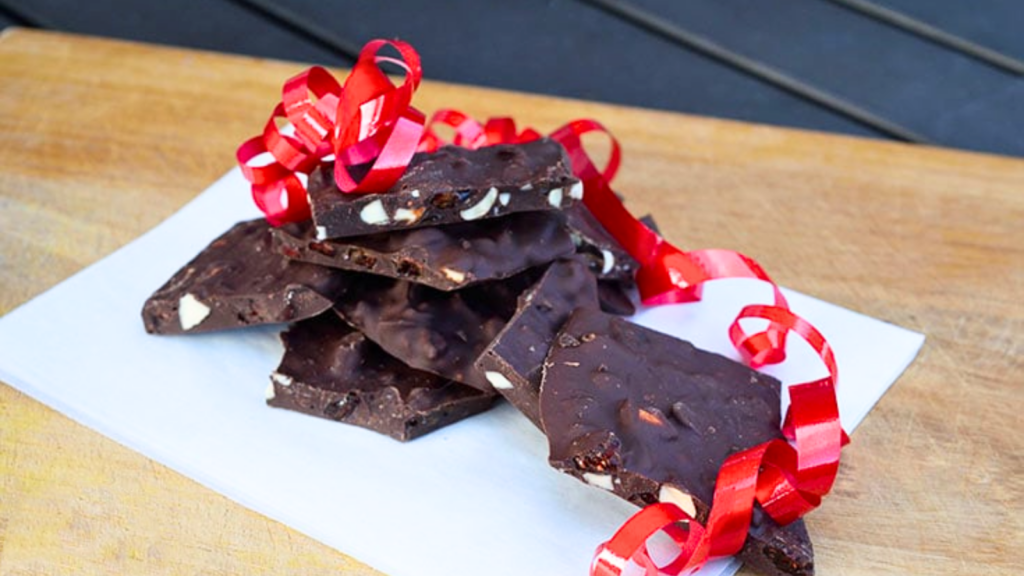 Chocolate Bark stacked up on a piece of parchment paper with a red ribbon on top.