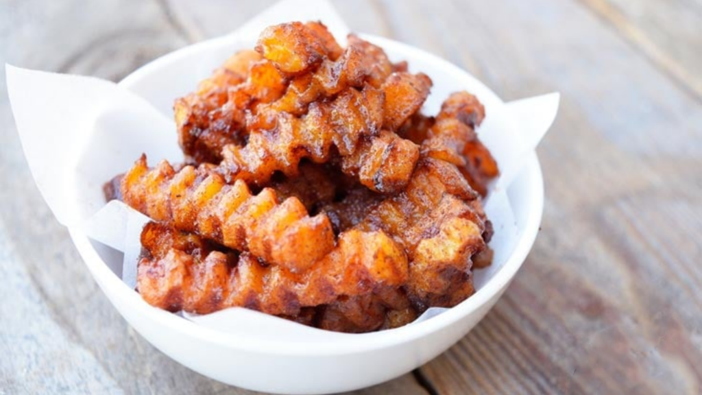 A white bowl holds a small pile of cinnamon butternut squash fries.