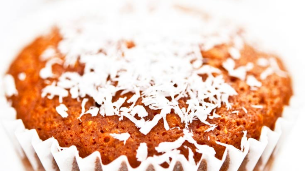 A single coconut pineapple muffin against a white background.