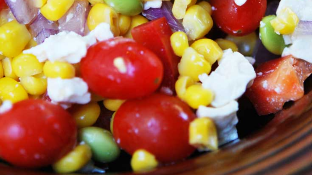 A brown bowl filled with corn salad.