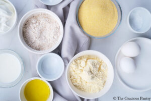 Cornbread Recipe ingredients in individual bowls on a white surface.