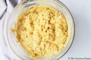 A glass bowl filled with Cornbread dough.