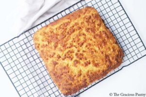 A loaf of cornbread cooling on a wire rack.