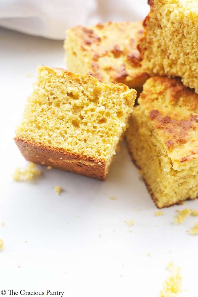 Four pieces of cornbread on a white surface.