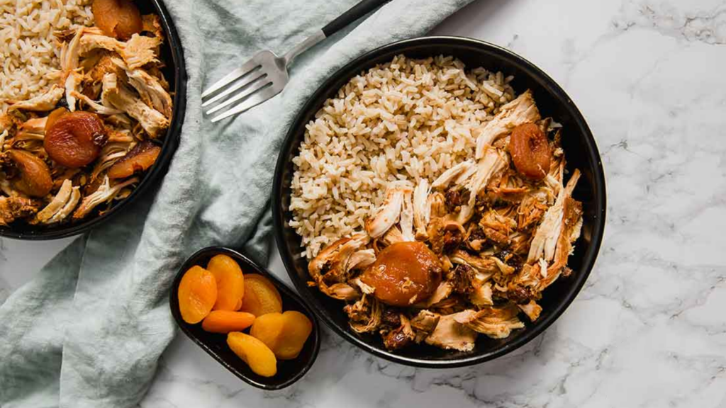 An overhead view of curry chicken shredded and served with rice and dried apricots.