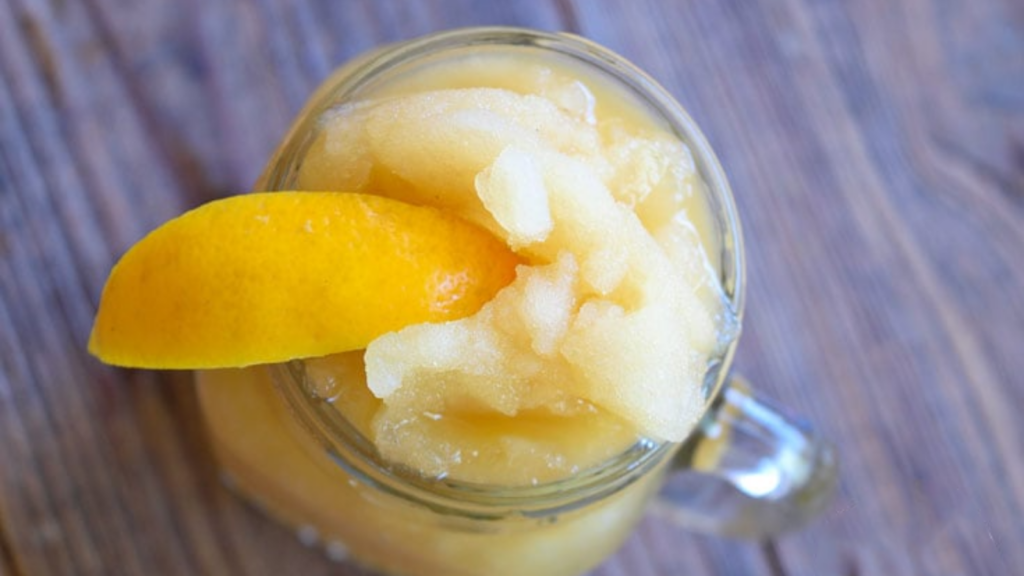An overhead view of a frosty virgin coconut sugar margarita in a glass jar garnished with a lemon wedge on the rim of the jar.