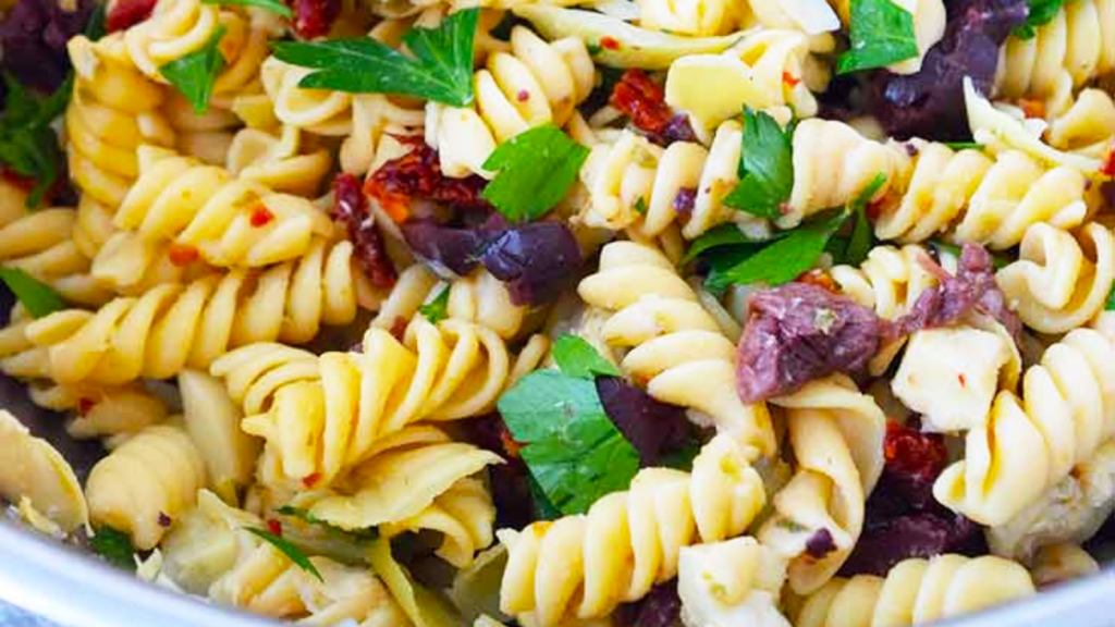 A closeup of a bowl filled with Greek pasta salad.