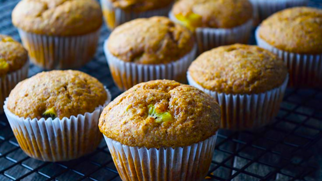 Rows of kiwi muffins cooling on a black wire rack.