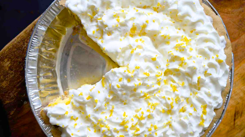 An overhead view looking down on a lemon cream pie with one slice removed.