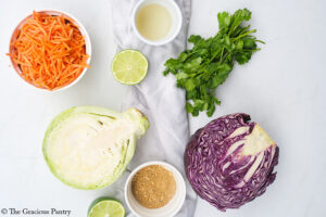Mexican Coleslaw Recipe ingredients gathered on a white surface.