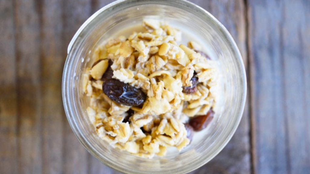 An overhead view of a small canning jar filled with overnight oats with raisins.