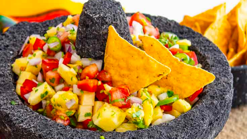 A closeup of a stone salsa dish filled with fresh pineapple salsa.