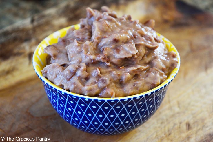 A small yellow and blue bowl filled with Refried Beans.