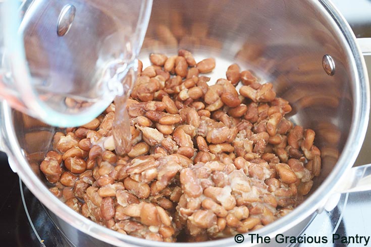 Adding water to cooked beans for this Refried Beans Recipe.