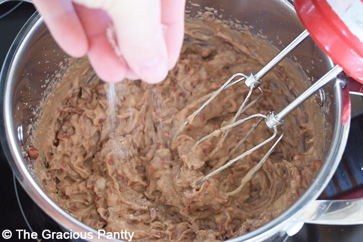 Seasoning refried beans with salt.