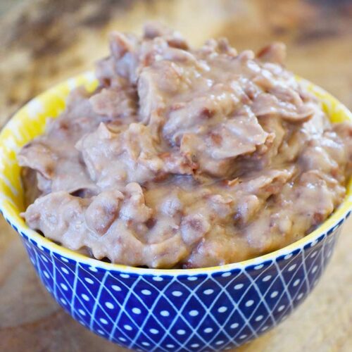 A side view of a yellow and blue bowl filled with refried beans.