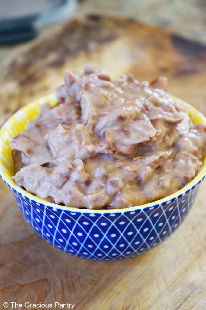 A side view of a yellow and blue bowl filled with healthy refried beans.