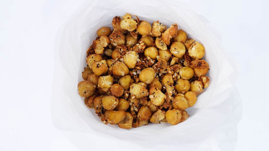 A funnel of parchment paper holds a batch of Roasted Everything Bagel Seasoning Chickpeas.