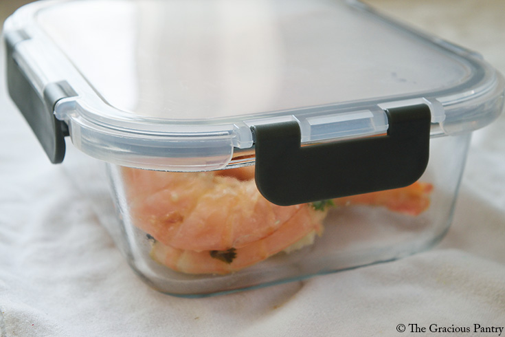 Leftover sheet pan garlic butter shrimp in a storage container with a lid.