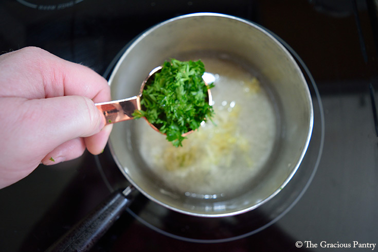 Adding fresh parsley to melting butter in a pot.