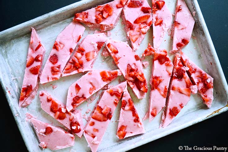 An overhead view of Strawberry Frozen Yogurt Bark pieces spread out over a metal cookie sheet.