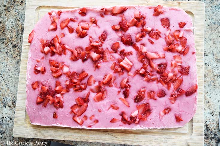 A full slab of Strawberry Frozen Yogurt Bark laying on a cutting board after freezing.