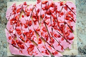 Chopped Strawberry Frozen Yogurt Bark laying on a cutting board.