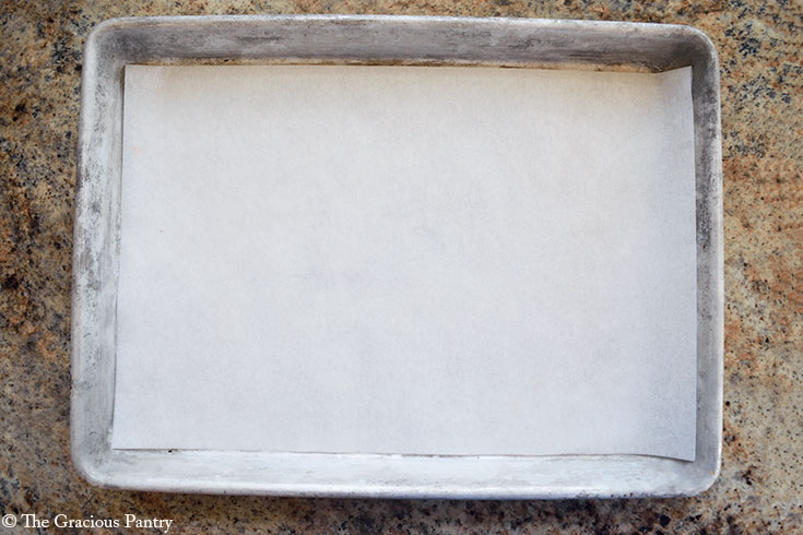 An overhead view of a cookie sheet lined with parchment paper.