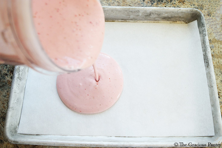 Pouring the blended ingredients onto a parchment-lined cookie sheet.