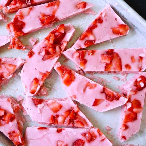 An overhead view of a sheet pan holding pieces of Strawberry Frozen Yogurt Bark.