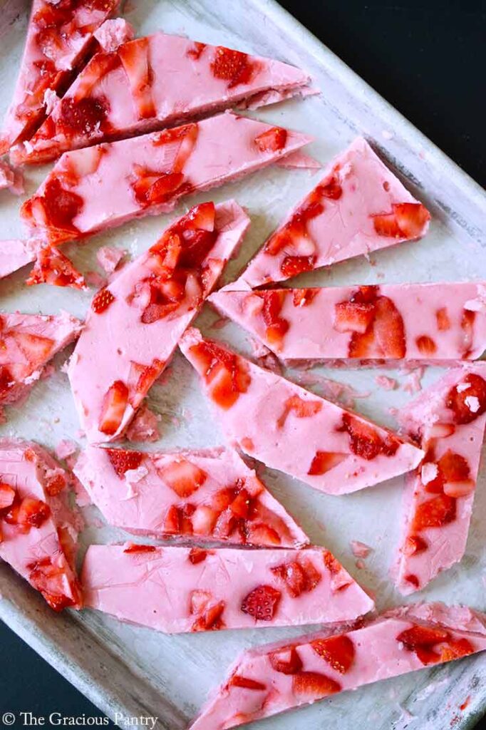 An overhead view of a sheet pan holding pieces of Strawberry Frozen Yogurt Bark.