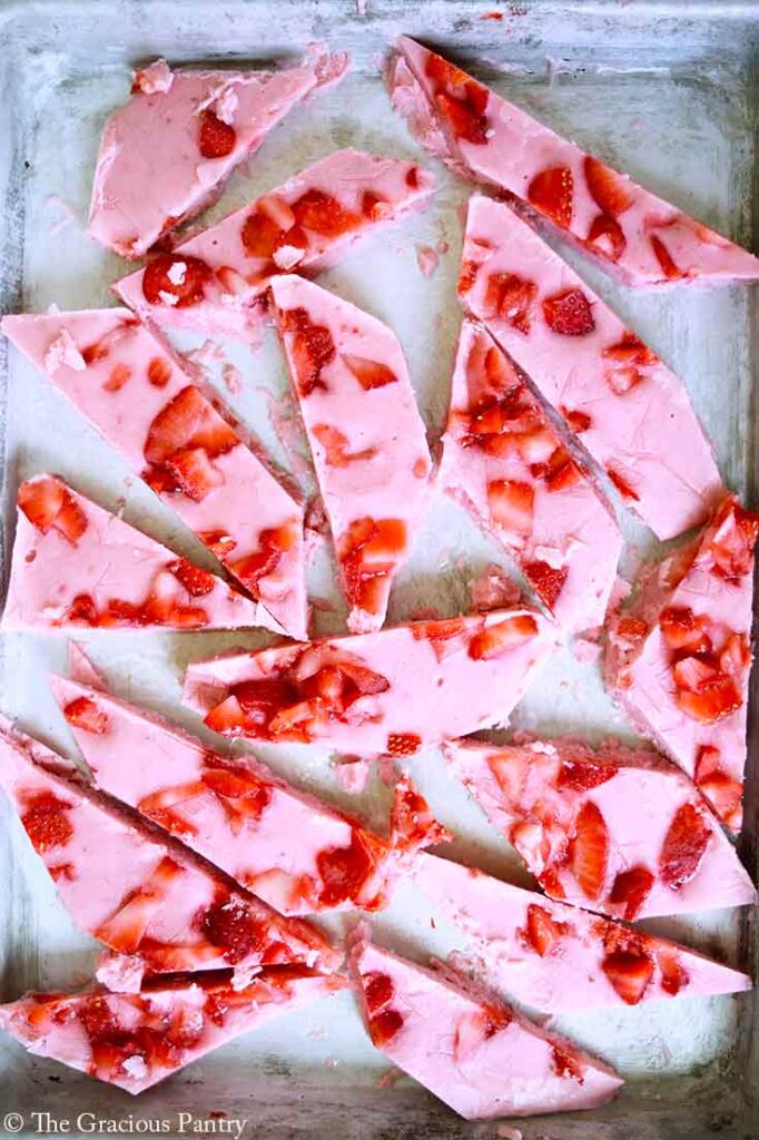 An overhead view of Strawberry Frozen Yogurt Bark pieces spread out over a baking sheet.