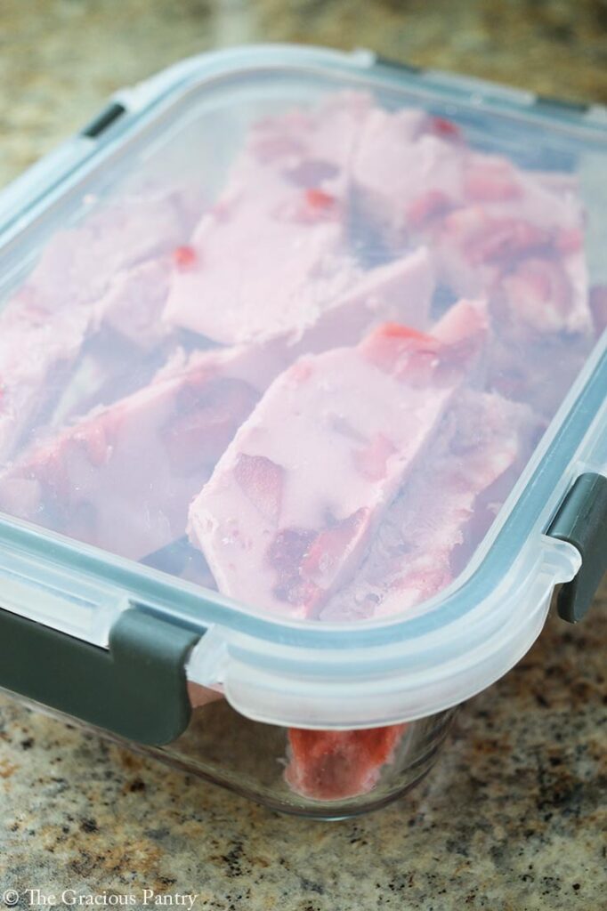 Strawberry Frozen Yogurt Bark pieces packed in a storage container.