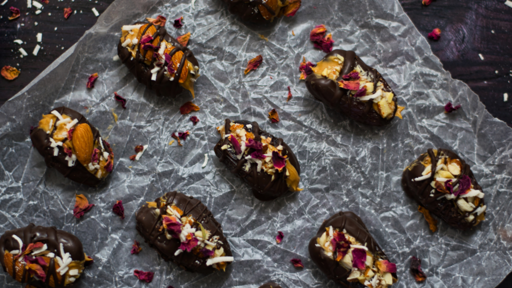 An overhead view of stuffed dates lined up on a piece of parchment paper.