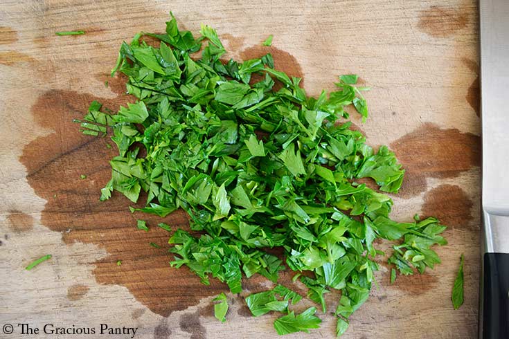 Fresh, chopped parsley on a wood cutting board.