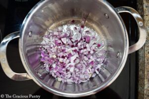 Onions sautéing in oil in a pot.