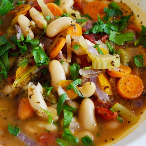 A closeup of a white bowl filled with White Bean Soup.