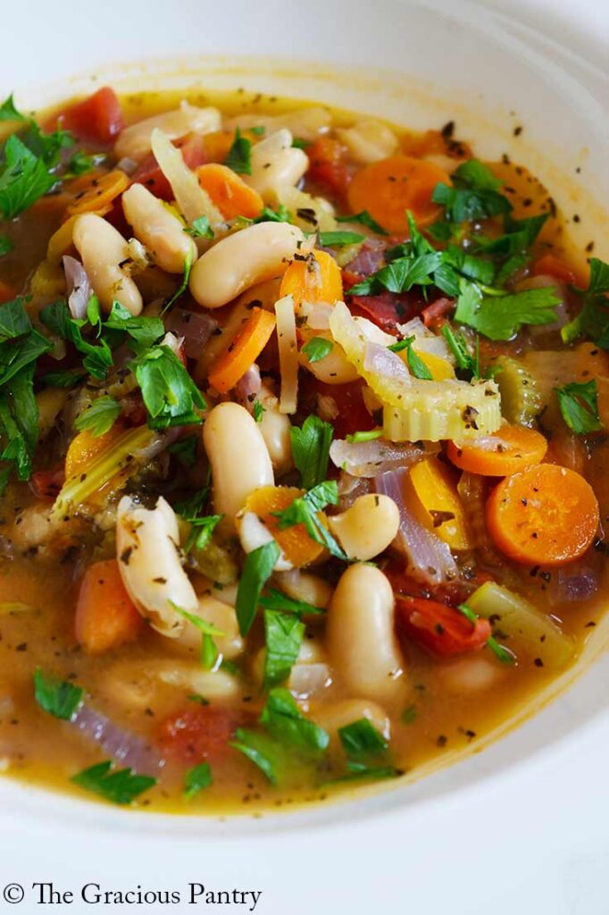 A closeup of a white bowl filled with White Bean Soup.