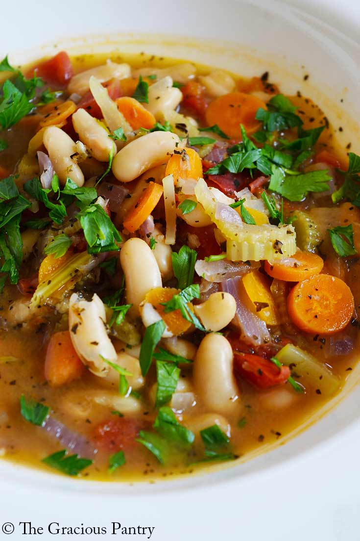 A closeup of a white bowl filled with White Bean Soup.