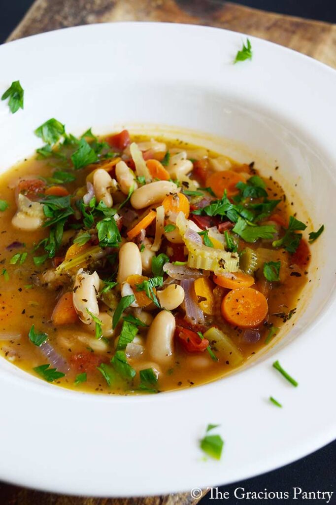 A front view of a white bowl filled with white bean soup.