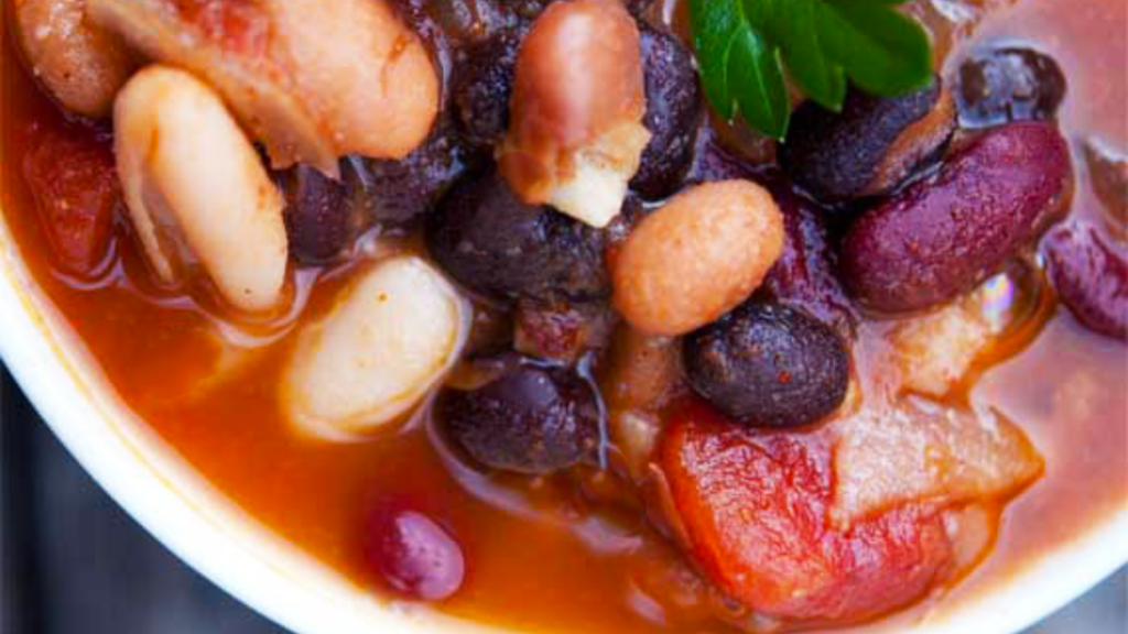 A closeup of a white bowl filled with 4 bean chili.