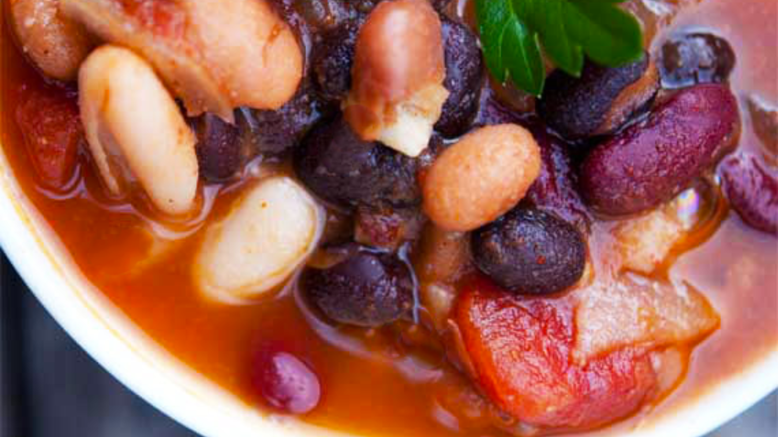 A closeup of a white bowl filled with 4 bean chili.