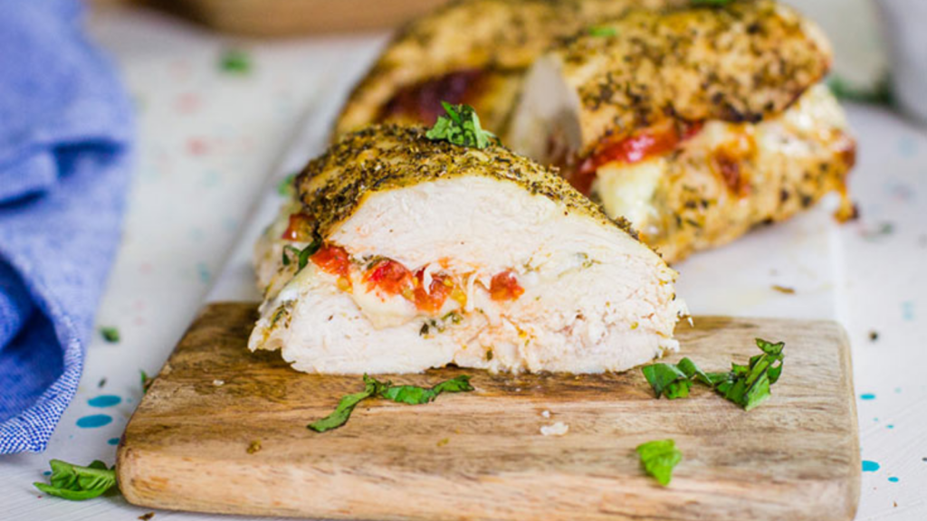 An air fryer chicken breast cut in half, showing the stuffing on the inside.