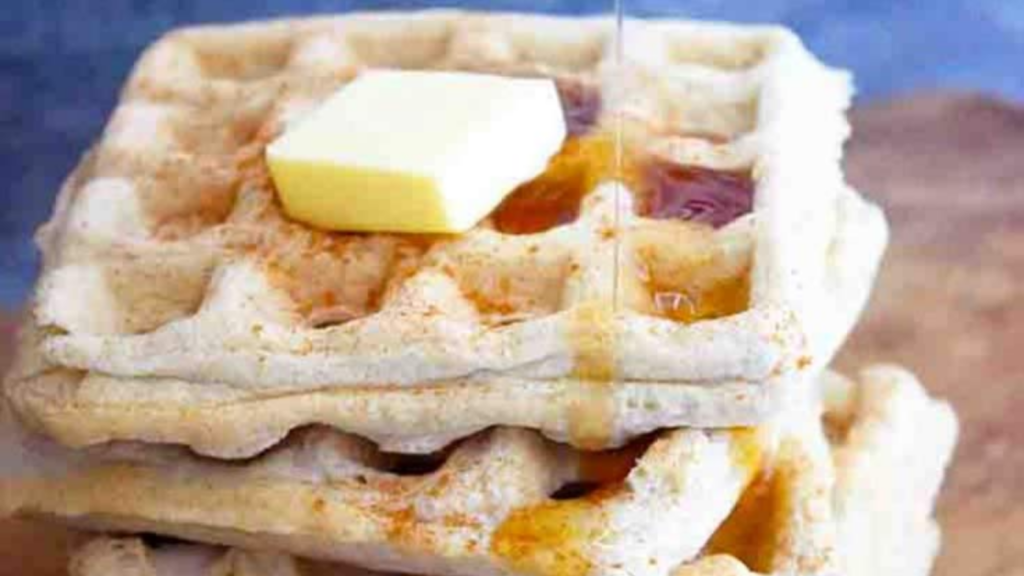 A stack of almond flour waffles with syrup and a pat of butter on top.