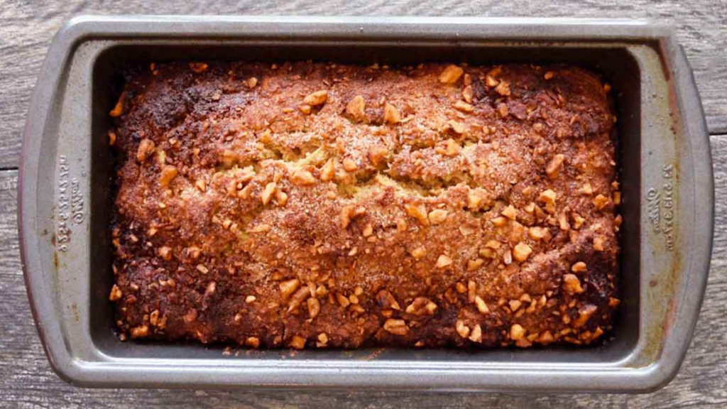 A loaf pan with a loaf of apple bread in it.