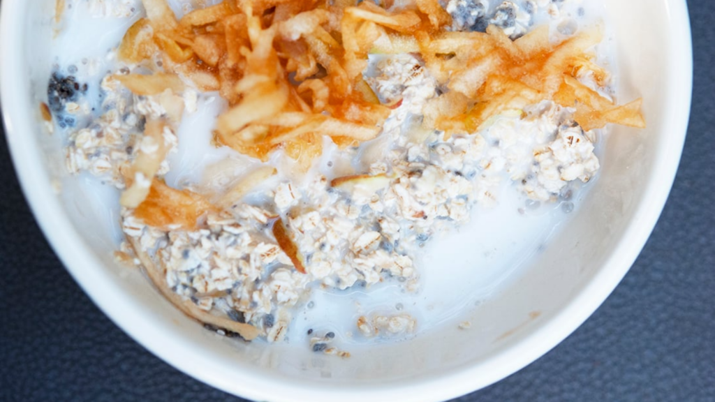 An overhead view of a white bowl filled with apple muesli.