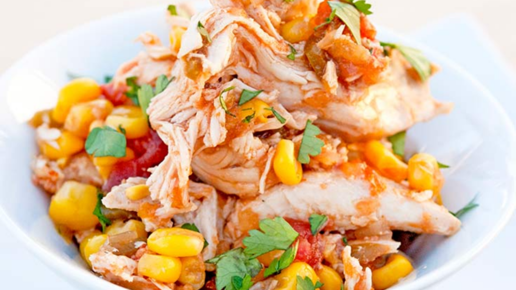A closeup of a white bowl filled with spicy sweet slow cooker chicken.