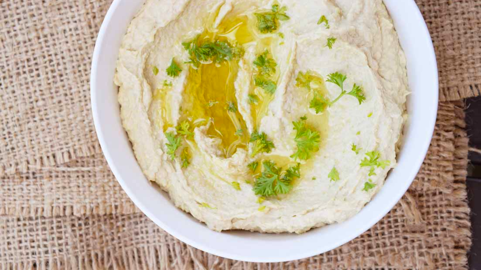 A white bowl filled with artichoke heart hummus.