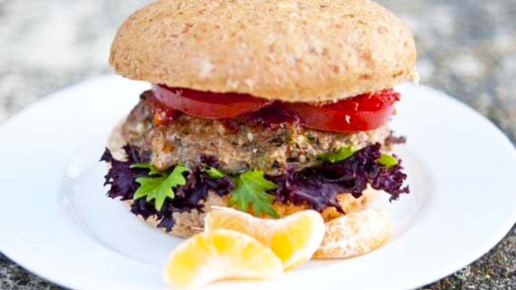 An Asian Portobello Mushroom Burger on a whole grain bun with tomato slices and lettuce.
