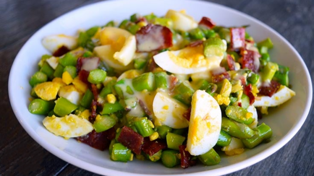 A white bowl holds asparagus salad.